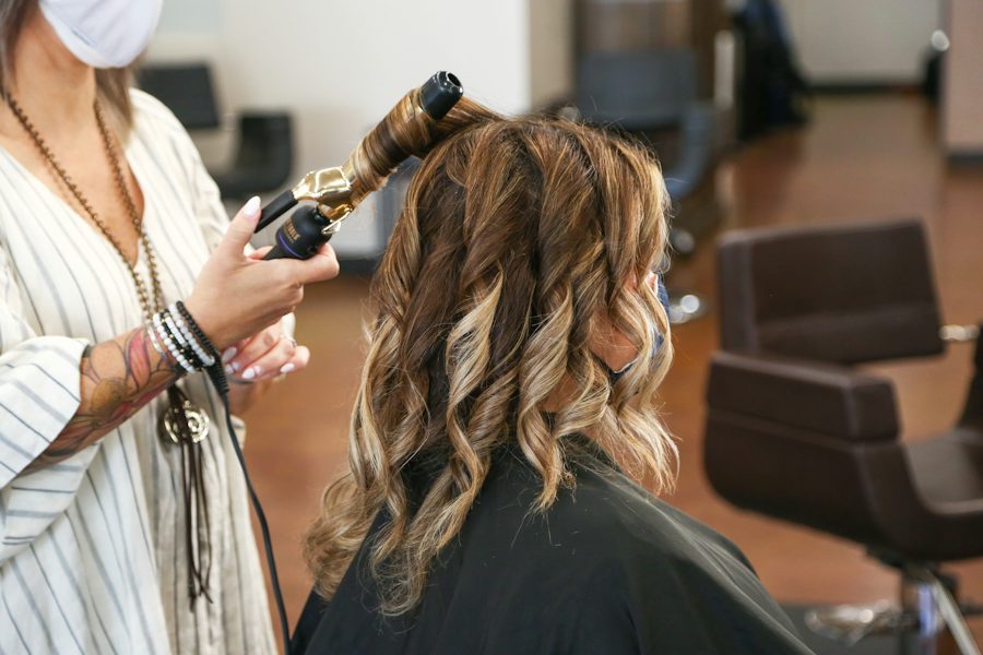 Stylist curling long hair with a curling iron